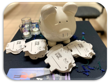 A Piggy bank with "pledge to save" forms for individuals to fill out